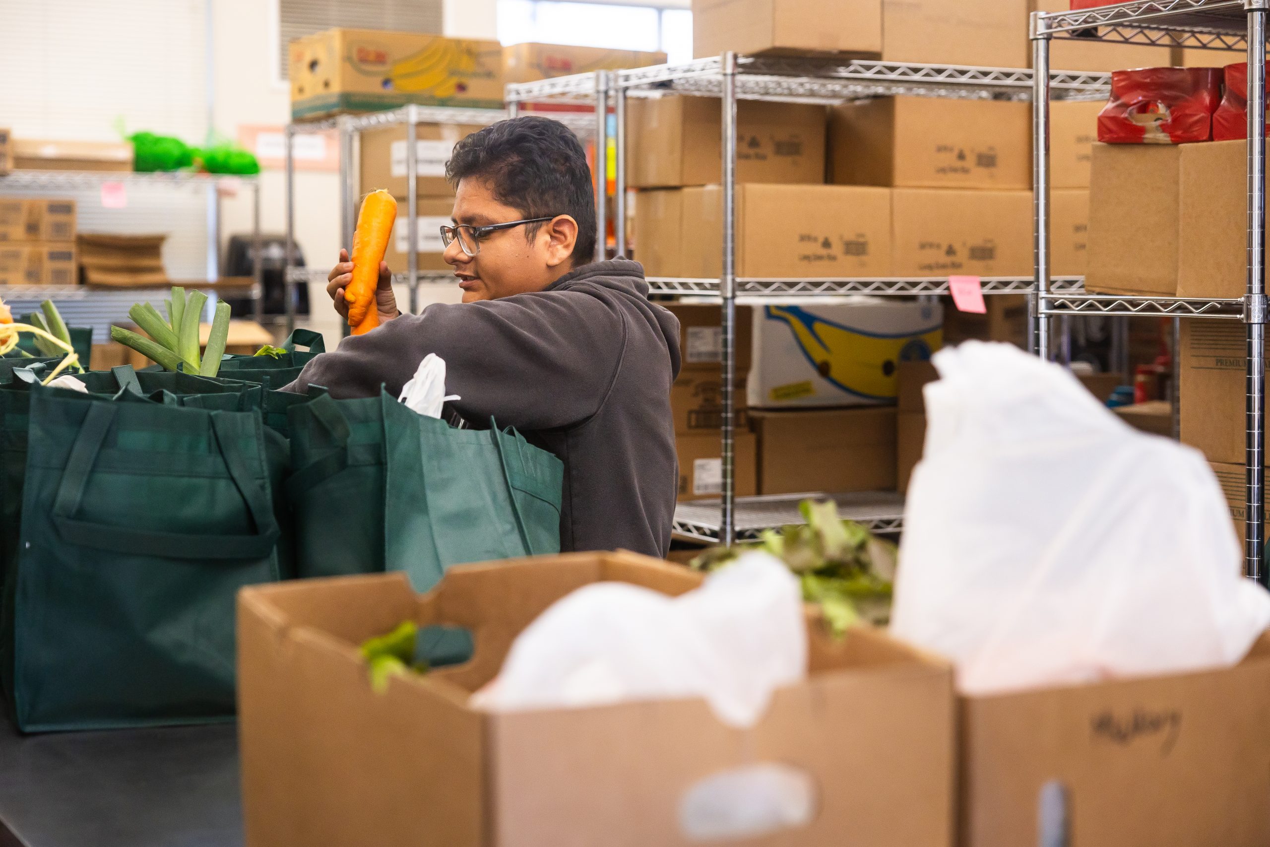 A College Corps member packs grocery bags for SCUSD families with Community Food Connections at the Alchemist CDC Food Access Center.